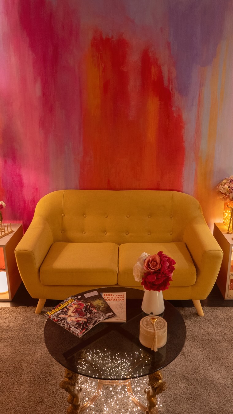 Interior del estudio Cardo Tattoo en Granada: sala de espera con sofá amarillo y mural colorido