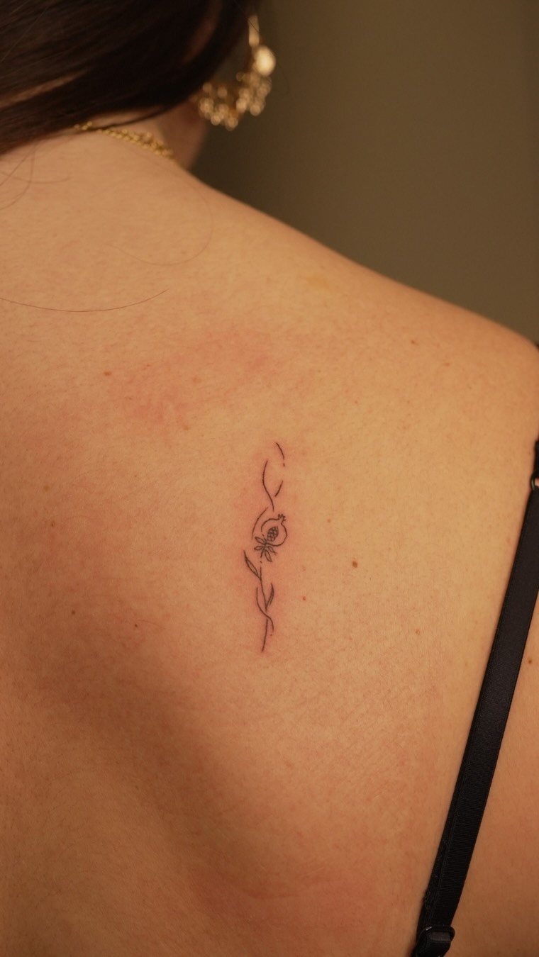 Tatuaje botánico de granada en fine line en la espalda, Cardo Tattoo
