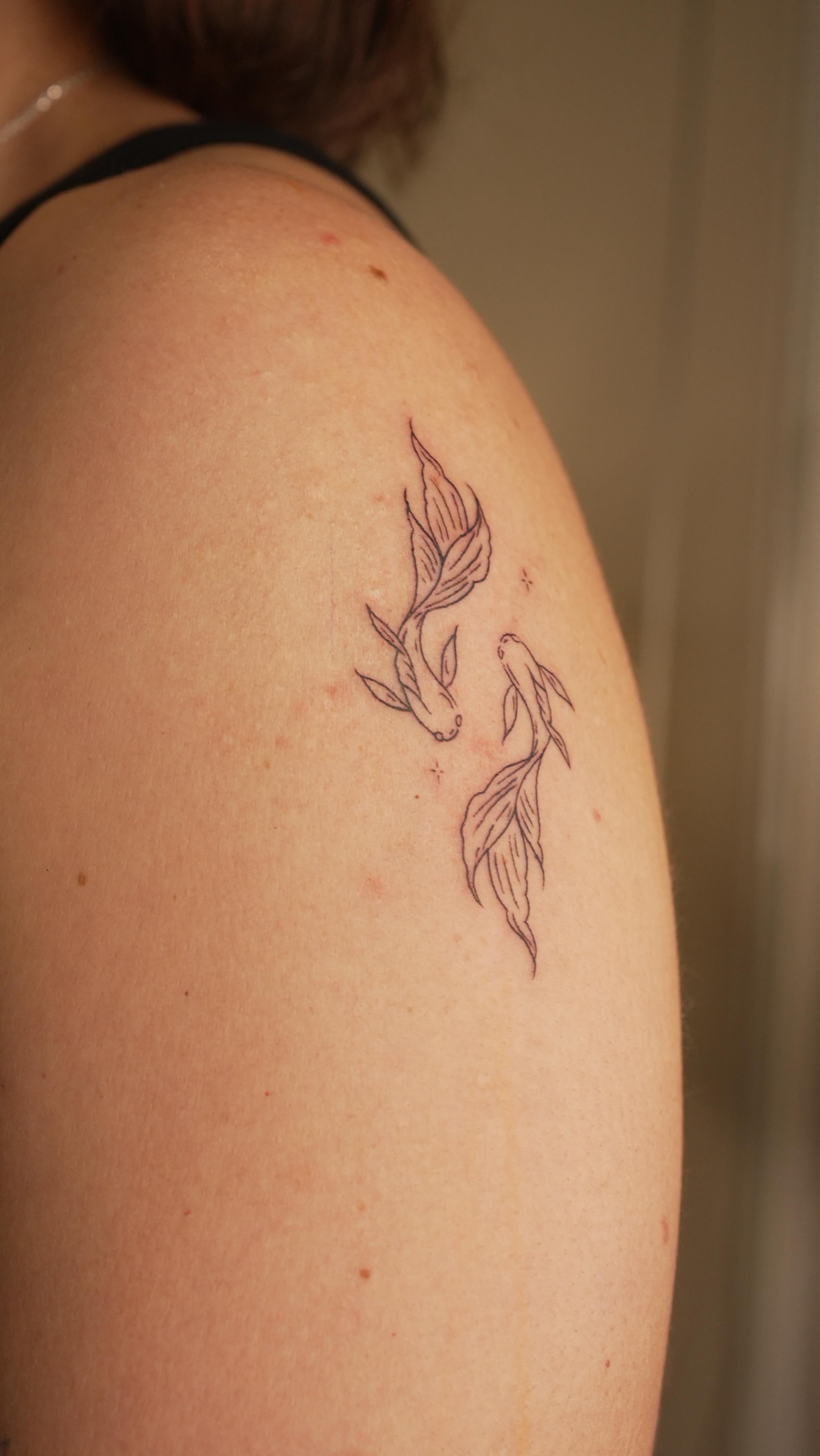 Tatuaje de peces koi en fine line en el hombro, estudio Cardo Tattoo Granada